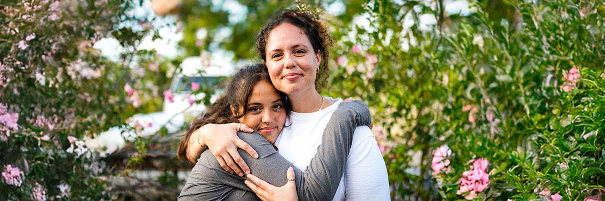 Woman and daughter hugging and smiling.